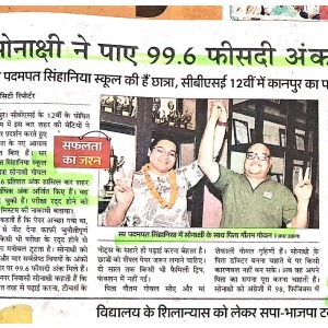 Newspaper photo: two men raise hands in celebration, one wearing a garland, amid a news article.