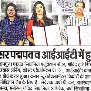 Three people stand holding open folders in a press conference, with a Hindi newspaper headline visible behind them or below.