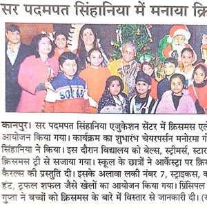 Group of students and adults posing at a festive ceremony, with a Christmas tree in the background.
