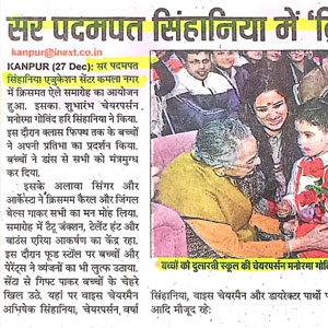 Hindi newspaper clipping about a Kanpur event; photo shows an elderly woman in a yellow shawl presenting something to a young child while others watch.