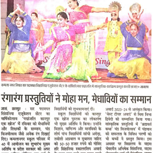 Group of women in colorful traditional outfits performing a folk dance on a stage, with a Hindi newspaper article visible beneath.