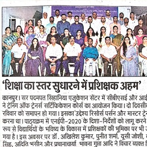 Large group of men and women in formal attire posing for a group photo at an education conference, banner visible in the background