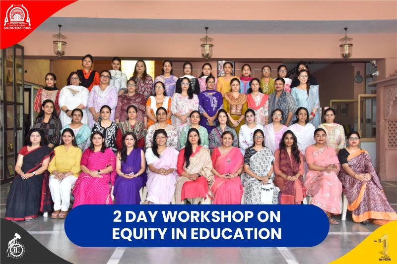 Group of women in colorful sarees posing for a group photo at a two-day workshop on equity in education, with a blue banner across the front.