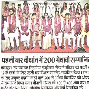 Group of students in colorful ceremonial attire posing on stage during the first graduation ceremony; banner reads 'First Graduation Ceremony'.