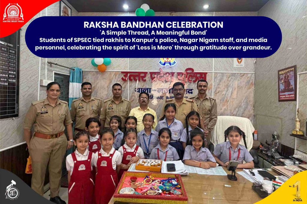 Less in Grandeur More in Gratitude Raksha Bandhan at SPSEC Group photo of police officers with smiling students during Raksha Bandhan celebration in a decorated room, banner in blue above.