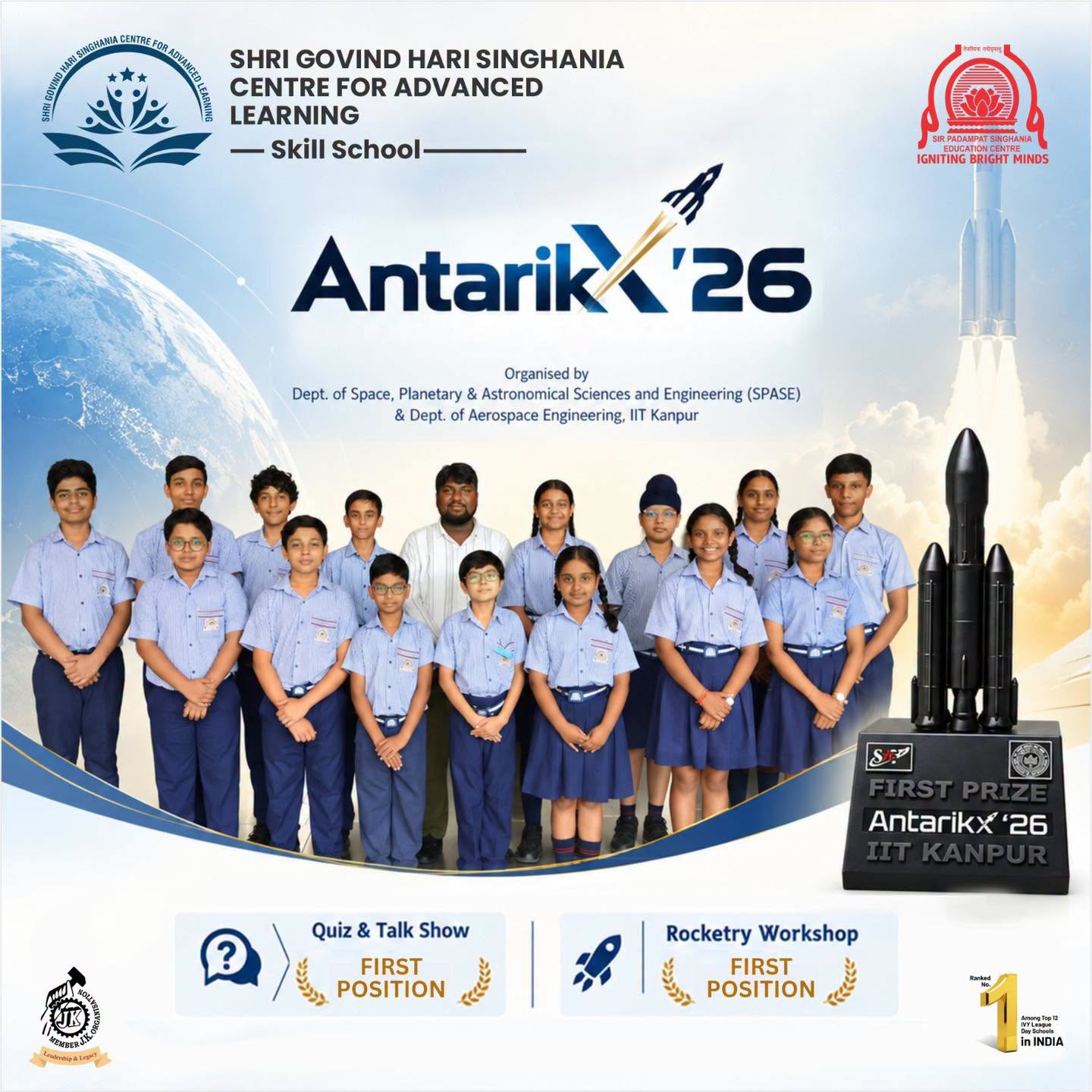 Group of students in blue uniforms posing in front of a space-themed poster for Antarikx'26, with a rocket trophy on the right side of the banner.
